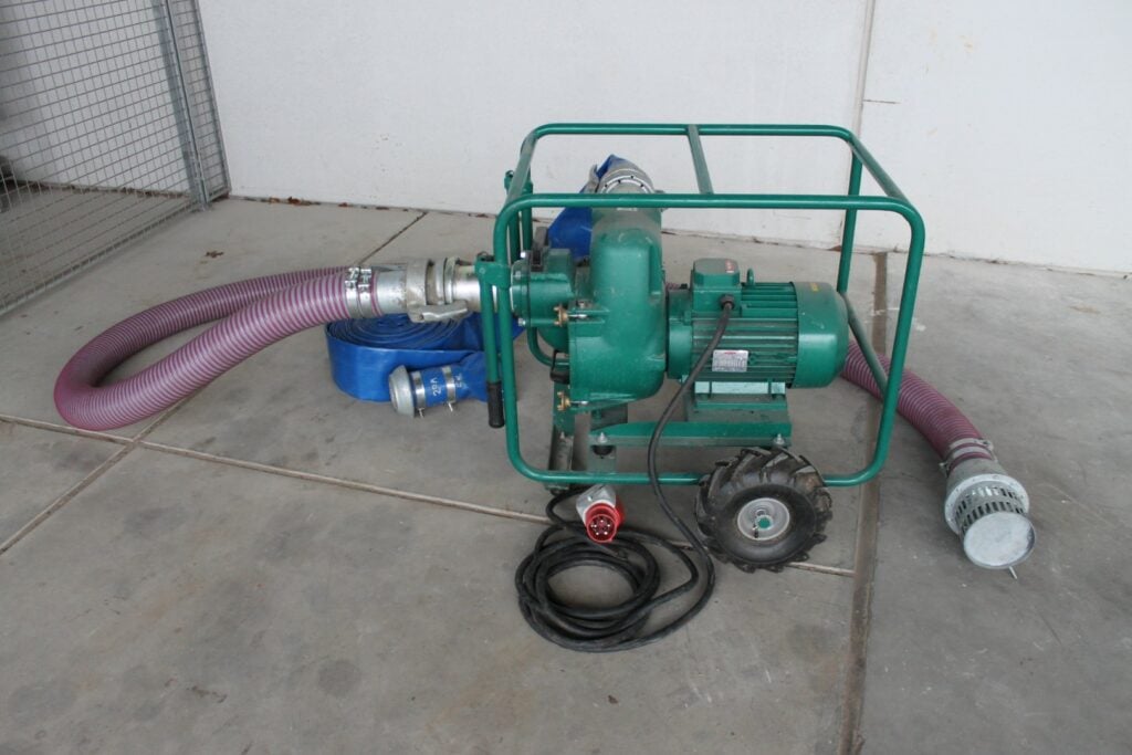 Groene centrifugaalpomp voor rioolwater, 145 m&sup3;/u, 400V met slangen en stroomkabel op betonnen vloer.