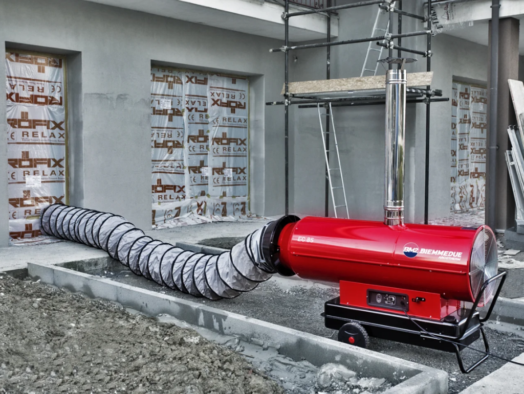Biemmedue Arcotherm EC85 dieselverwarming met schouw en flexibele warmeluchtslang op een bouwwerf