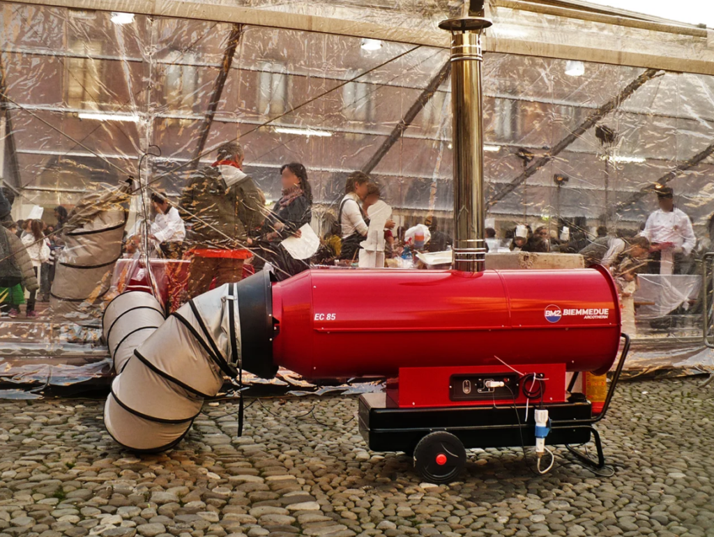 Biemmedue Arcotherm EC85 dieselverwarming met schouw en warmeluchtslang naast een evenemententent