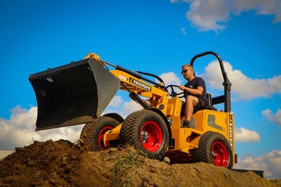 Gele Knikmops 130 kniklader 1450kg met schepbak aan het werk op een werf - Euro Rent
